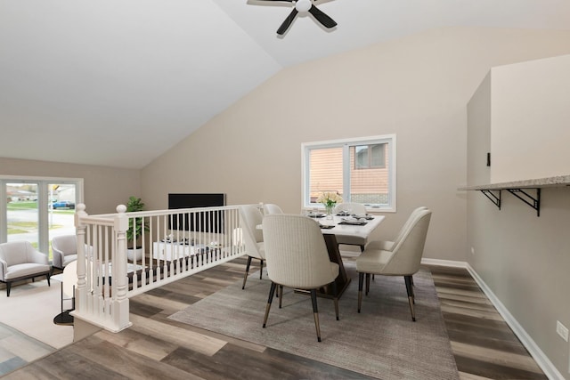 dining space with baseboards, wood finished floors, and vaulted ceiling