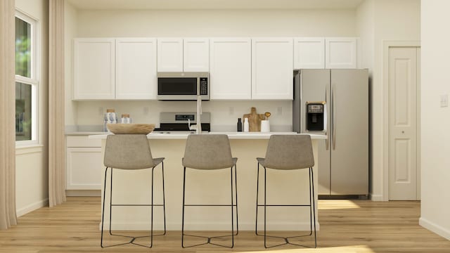 kitchen featuring light hardwood / wood-style flooring, white cabinets, an island with sink, and stainless steel appliances