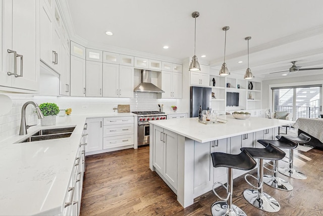 kitchen featuring sink, high end range, a center island, white cabinets, and wall chimney exhaust hood