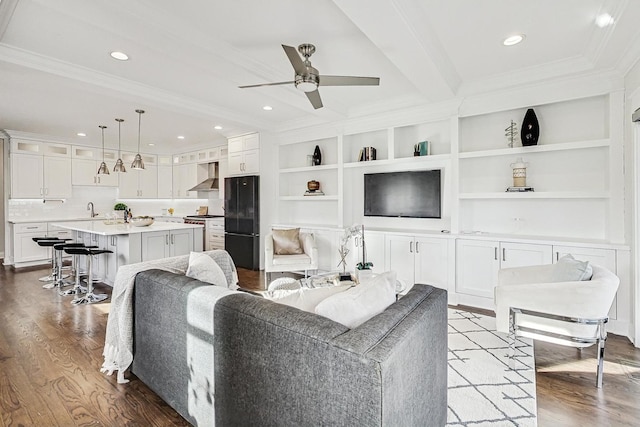 living room featuring sink, light hardwood / wood-style flooring, ornamental molding, beamed ceiling, and ceiling fan