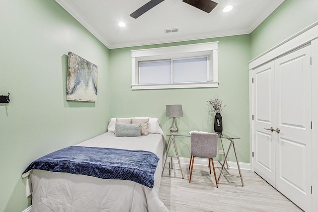 bedroom with crown molding, ceiling fan, light hardwood / wood-style floors, and a closet