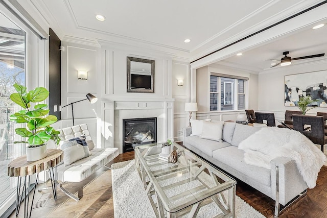 living room with wood-type flooring, ornamental molding, and ceiling fan