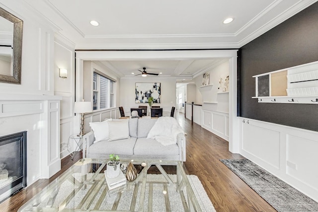 living room with ceiling fan, ornamental molding, a high end fireplace, and wood-type flooring