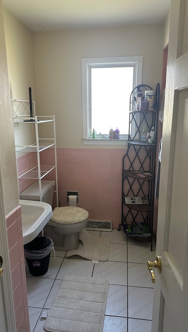 bathroom featuring tile patterned floors, sink, tile walls, and toilet