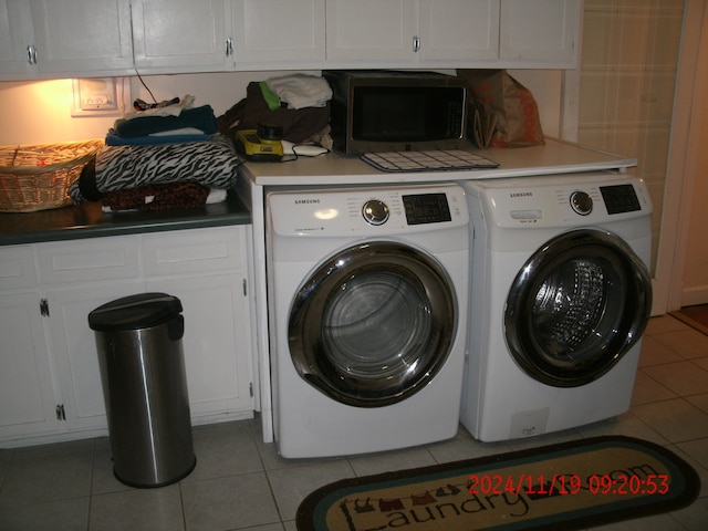 clothes washing area featuring washing machine and clothes dryer, light tile patterned floors, and cabinets