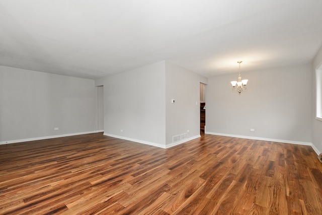 empty room featuring a chandelier and dark hardwood / wood-style flooring