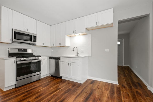 kitchen with backsplash, dark wood-type flooring, white cabinets, sink, and stainless steel appliances