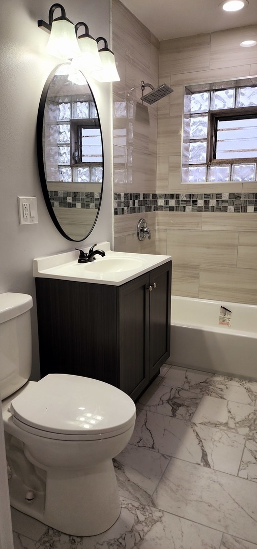 full bathroom featuring vanity, toilet, and tiled shower / bath