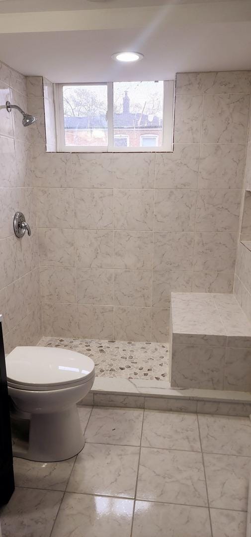 bathroom featuring toilet and a tile shower