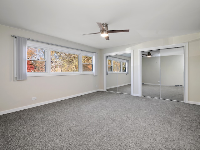 unfurnished bedroom with carpet, ceiling fan, and two closets