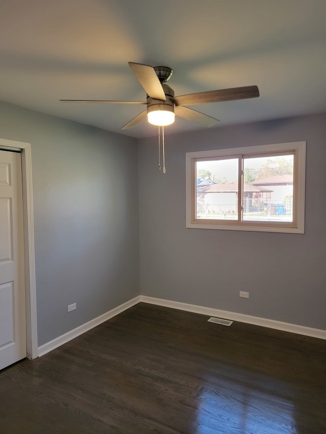 empty room with ceiling fan and dark hardwood / wood-style flooring