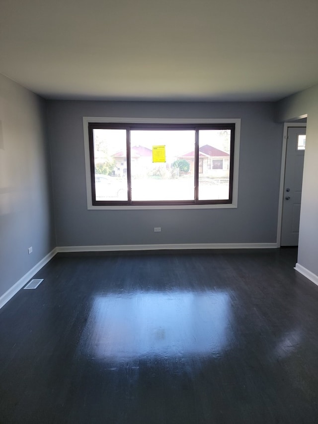 spare room with dark hardwood / wood-style flooring and plenty of natural light