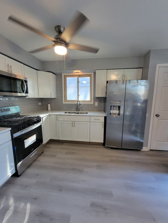 kitchen featuring stainless steel appliances, white cabinets, sink, and light hardwood / wood-style flooring