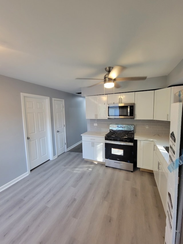 kitchen featuring stainless steel appliances, white cabinetry, light wood-type flooring, and decorative backsplash