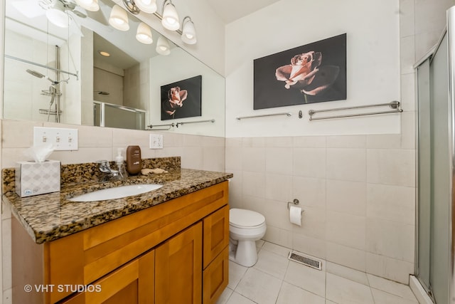 bathroom featuring tile walls, a shower with door, vanity, tile patterned flooring, and toilet