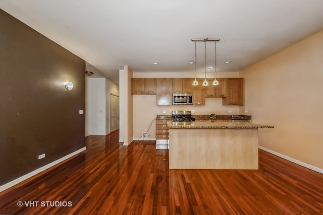 kitchen featuring stainless steel appliances, dark wood-type flooring, light stone counters, an island with sink, and decorative light fixtures