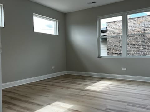 empty room featuring light wood-type flooring and a healthy amount of sunlight