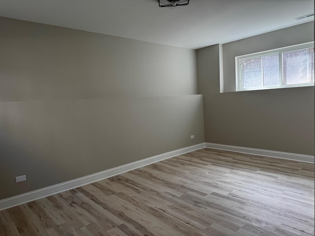 spare room with baseboards, visible vents, and wood finished floors
