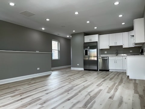 kitchen with light hardwood / wood-style floors, white cabinetry, sink, and appliances with stainless steel finishes