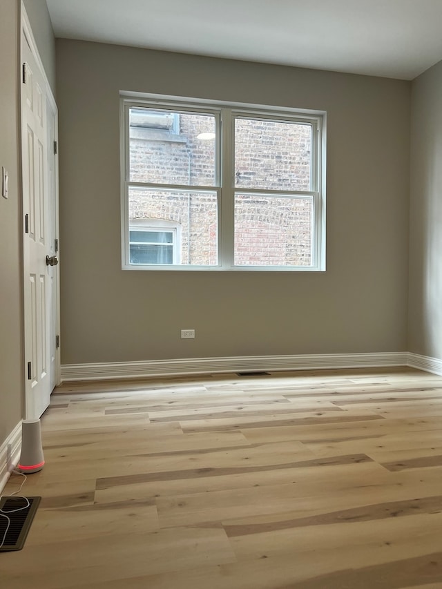 spare room featuring a wealth of natural light and light hardwood / wood-style floors