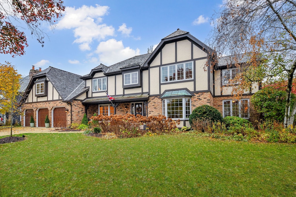 tudor-style house featuring a front yard and a garage