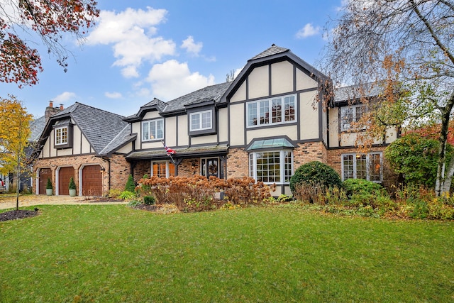 tudor-style house featuring a front yard and a garage