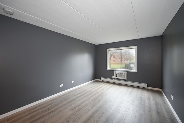 spare room featuring baseboard heating and hardwood / wood-style flooring