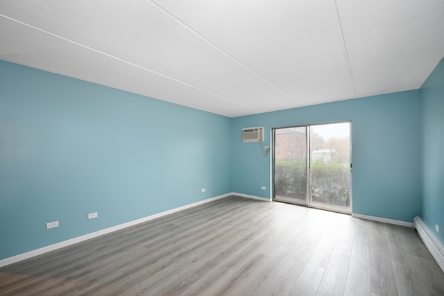 unfurnished room with hardwood / wood-style flooring, a wall mounted AC, and a baseboard heating unit