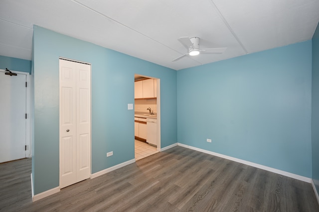 unfurnished bedroom featuring a closet, wood-type flooring, connected bathroom, sink, and ceiling fan