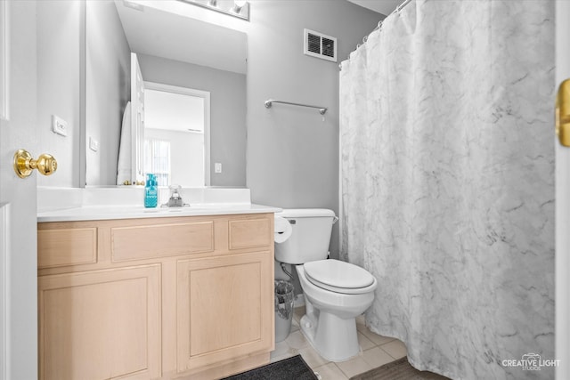 bathroom with toilet, vanity, and tile patterned floors