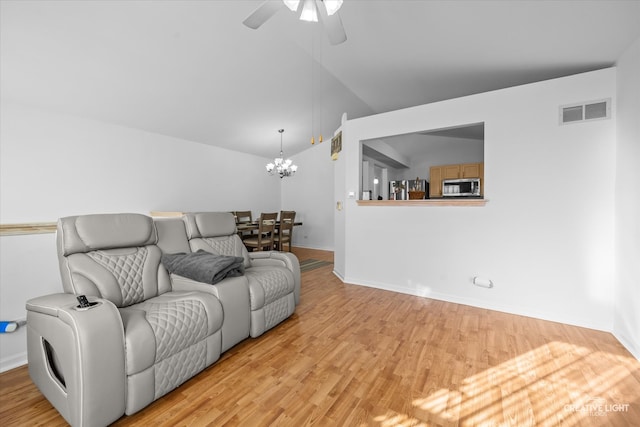 living room featuring vaulted ceiling, ceiling fan with notable chandelier, and light hardwood / wood-style flooring