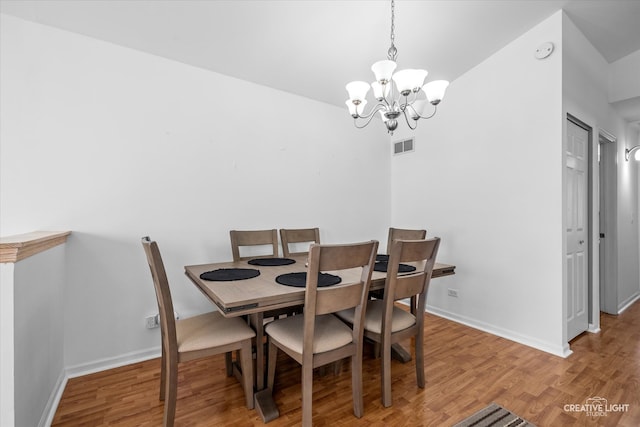 dining room with a chandelier, vaulted ceiling, and hardwood / wood-style flooring