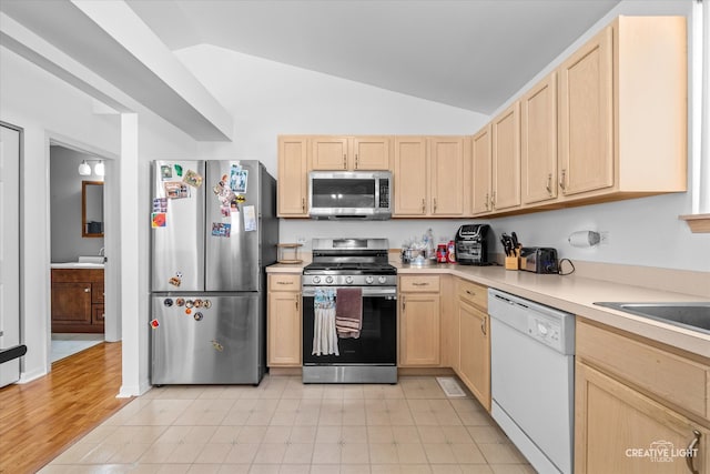 kitchen with lofted ceiling, light brown cabinetry, light hardwood / wood-style flooring, and appliances with stainless steel finishes