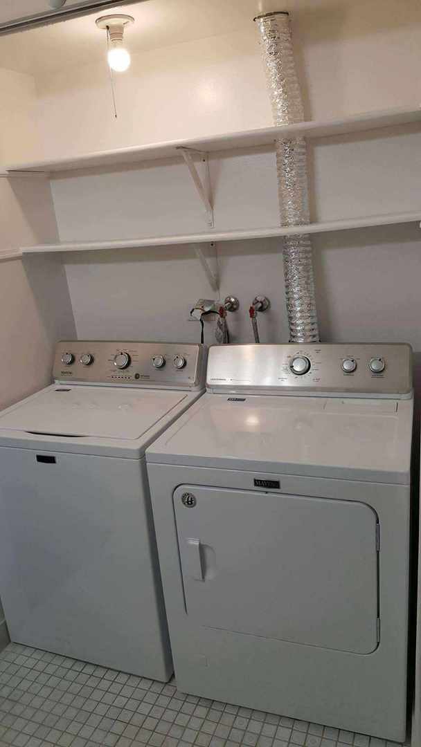 clothes washing area featuring washer and clothes dryer and light tile patterned floors