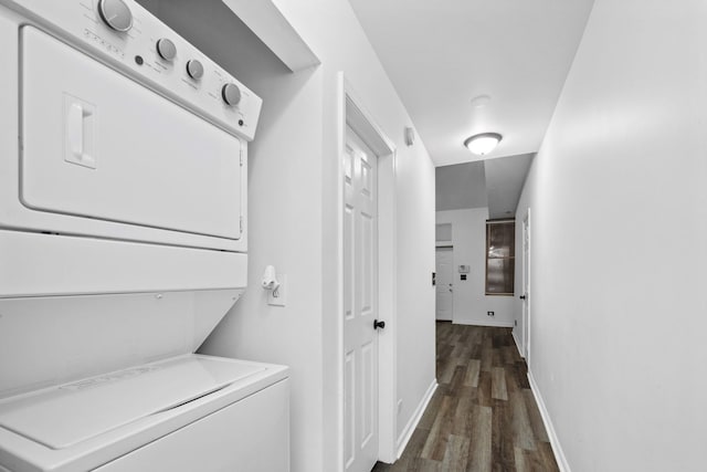 washroom featuring dark hardwood / wood-style flooring and stacked washer / dryer