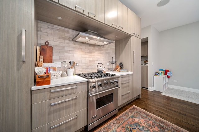 kitchen featuring dark wood-type flooring, luxury range, wall chimney range hood, and tasteful backsplash