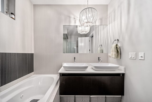 bathroom featuring vanity, a notable chandelier, and tiled tub