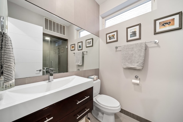 bathroom featuring a shower with shower door, vanity, toilet, and tile patterned floors