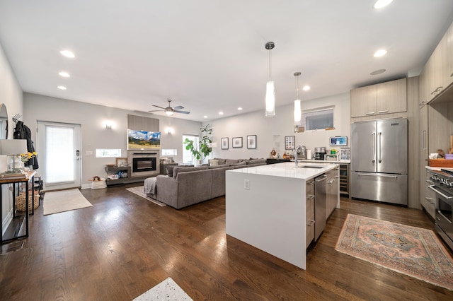 kitchen with stainless steel appliances, dark hardwood / wood-style floors, a center island with sink, and sink