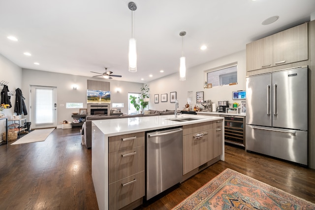 kitchen featuring stainless steel appliances, wine cooler, sink, an island with sink, and dark wood-type flooring