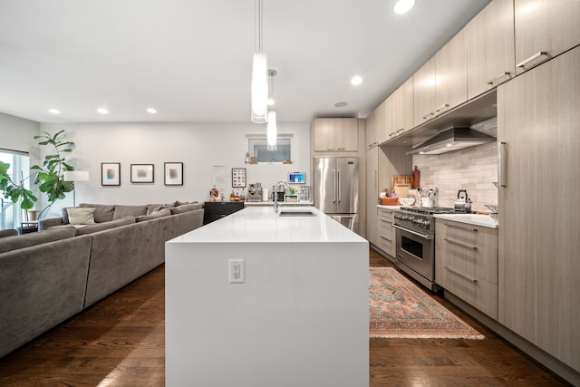 kitchen with stainless steel appliances, sink, decorative light fixtures, an island with sink, and dark wood-type flooring