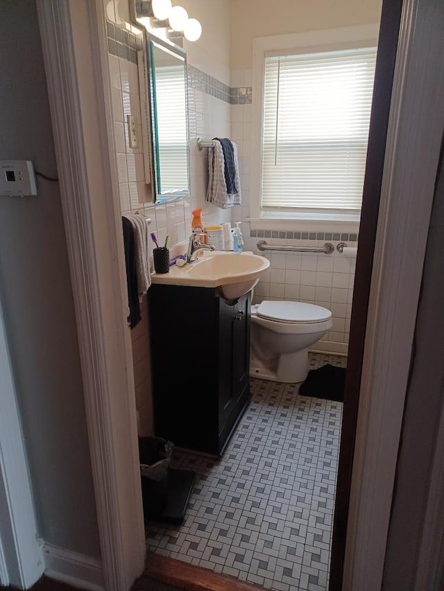 bathroom with tile patterned flooring, vanity, toilet, and tile walls