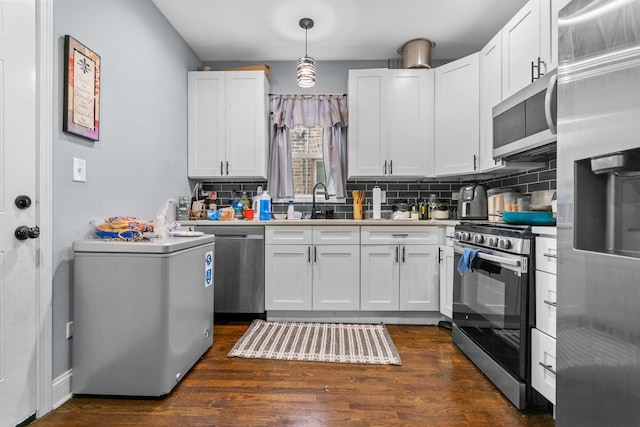 kitchen featuring pendant lighting, stainless steel appliances, white cabinetry, and dark wood-type flooring