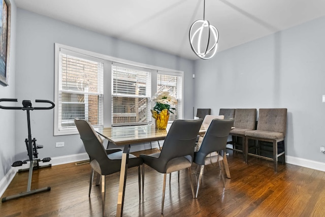 dining area featuring dark wood-type flooring and an inviting chandelier