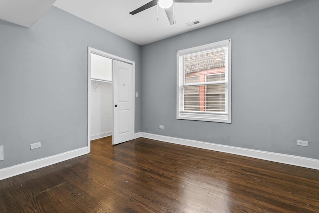 unfurnished bedroom with ceiling fan, a closet, and dark wood-type flooring