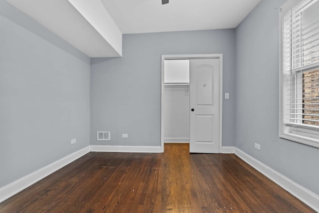 unfurnished bedroom with dark hardwood / wood-style floors, a walk in closet, and a closet