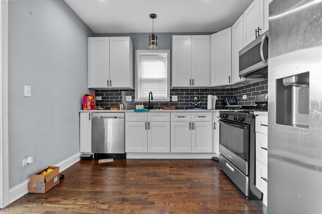 kitchen featuring dark wood-type flooring, white cabinetry, hanging light fixtures, and stainless steel appliances