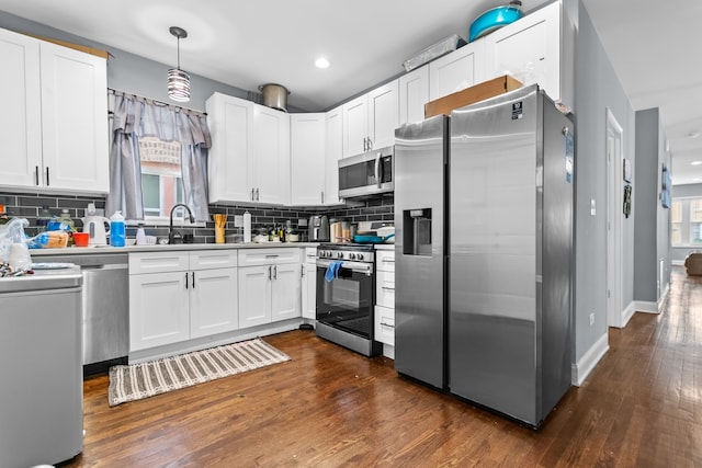 kitchen featuring hanging light fixtures, white cabinets, and stainless steel appliances