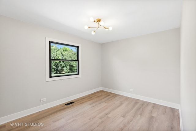 unfurnished room featuring a chandelier and light wood-type flooring