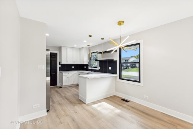 kitchen featuring light hardwood / wood-style floors, white cabinetry, sink, an inviting chandelier, and hanging light fixtures